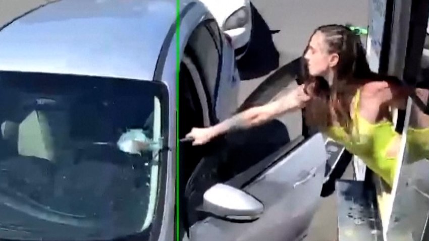 Woman smashing a windshield with a hammer.