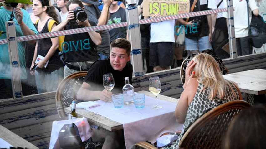 A man ducks and a woman covers her ears as protesters interrupt their meal in Barcelona.