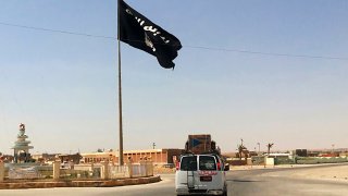 A motorist passes by a flag of the Islamic State group.