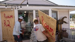 A worker boards up windows at a store ahead of Hurricane Beryl's landfall in Port Aransas, Texas