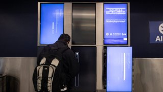 A Delta technician works on a set of screens displaying a blue page and reading “Recovery” in Terminal 2, Delta Airlines, at Los Angeles airport, on July 19, 2024. Airlines, banks, TV channels and other businesses were disrupted worldwide on Friday following a major computer systems outage linked to an update on an antivirus program.