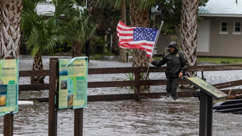 A Florida Fish and Wildlife Commission officer removes a US flag from the flood waters after Hurricane Debby made landfall in Suwannee, Florida, US, on Monday, Aug. 5, 2024. Tropical Storm Debby threatens to unleash days of heavy rain and flooding on the US East Coast after slamming into Florida as a hurricane, knocking out power to thousands. Photographer: Christian Monterrosa/Bloomberg via Getty Images