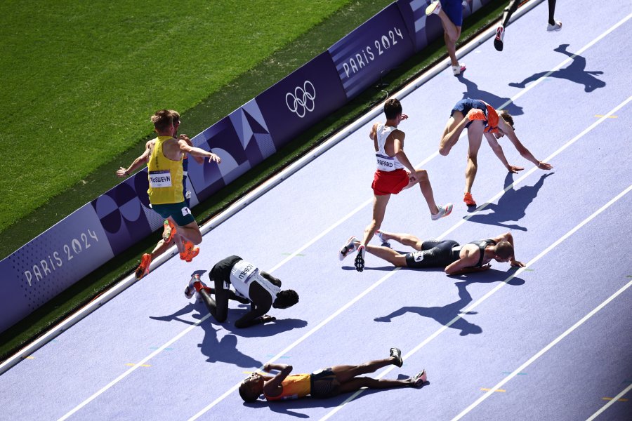 Spain's Thierry Ndikumwenayo, Refugee Team's Dominic Lokinyomo Lobalu, Britain's George Mills and Netherlands' Mike Foppen fall as they compete in the men's 5000m heat of the athletics event at the Paris 2024 Olympic Games at Stade de France in Saint-Denis, north of Paris, on August 7, 2024