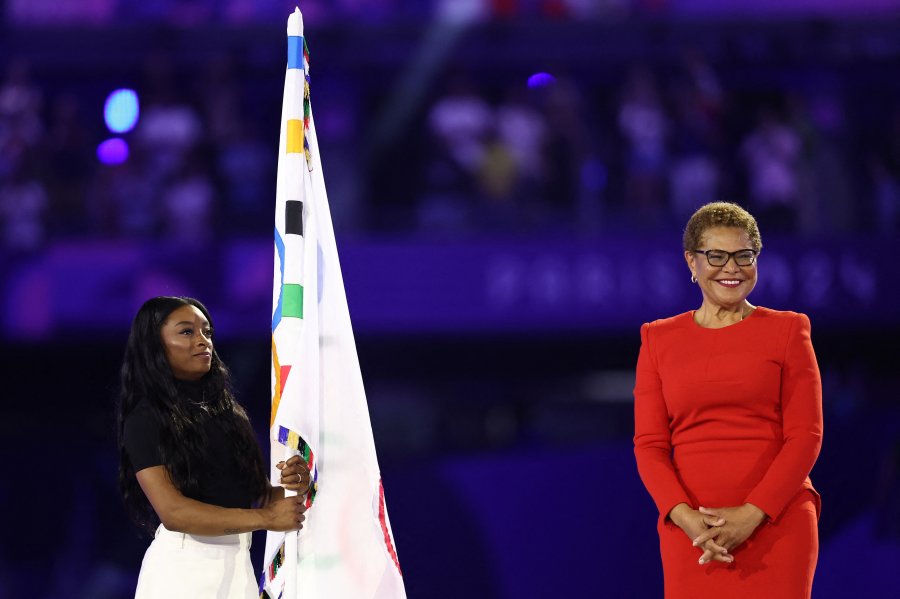 US' gymnasts Simone Biles holds the Olympic flag next to Los Angeles' Mayor Karen Bass