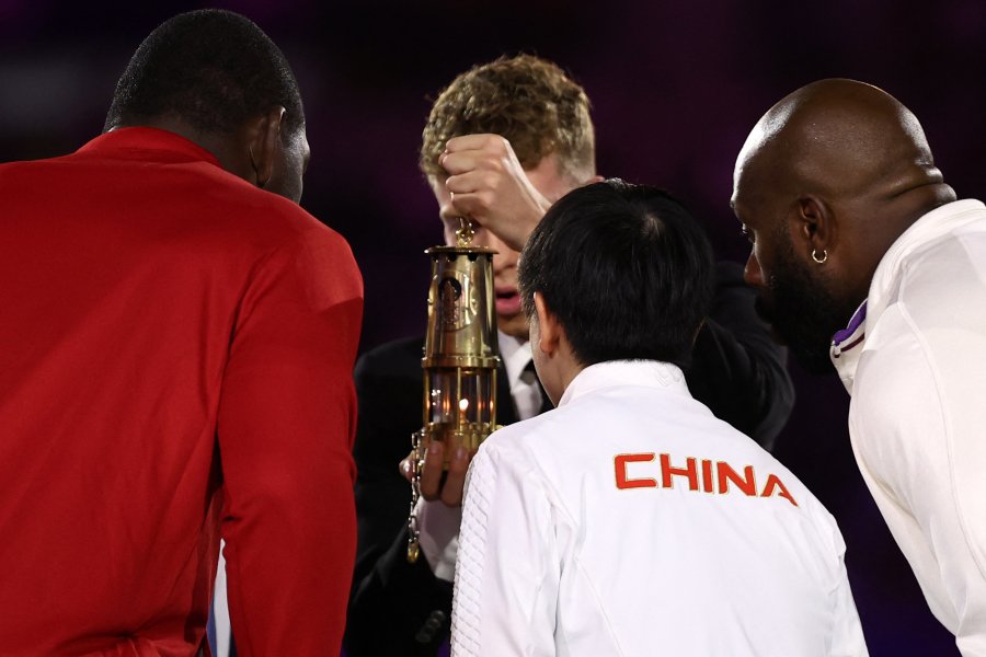 France's swimmer Leon Marchand arrives with the Olympic flame