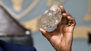 Botswana’s President Mokgweetsi Masisi holds a large diamond discovered in Botswana at his office in Gaborone on August 22, 2024.