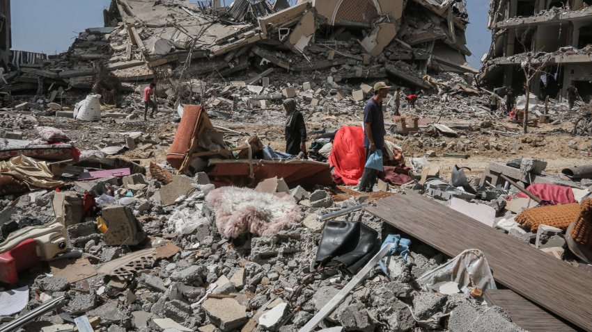 Palestinians search the rubble of destroyed buildings