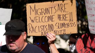 A protester holds up a placard during a rally staged by the East Colfax Community Collective