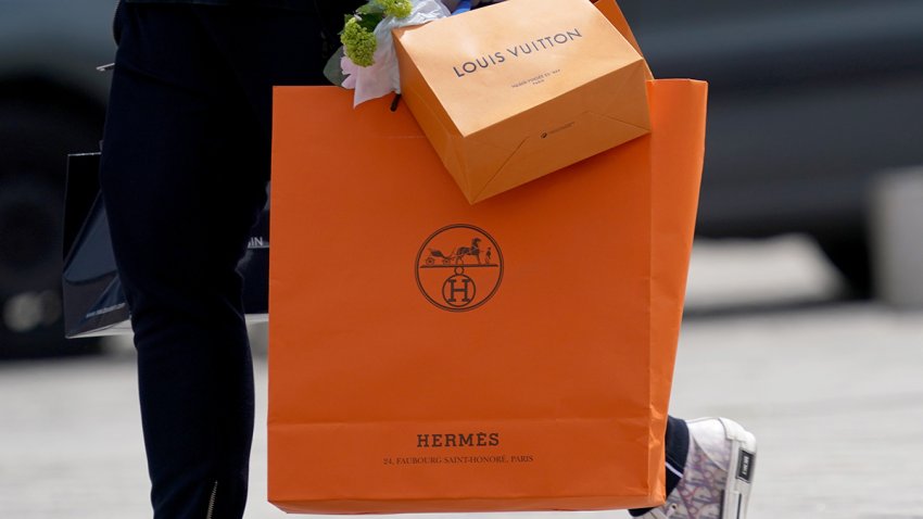 PARIS, FRANCE – MAY 11: A passerby wears Dior B23 sneakers and holds a Hermes orange shopping paper bag and a Louis Vuitton shopping bag, in the streets of Paris, on May 11, 2020 in Paris, France. (Photo by Edward Berthelot/Getty Images)