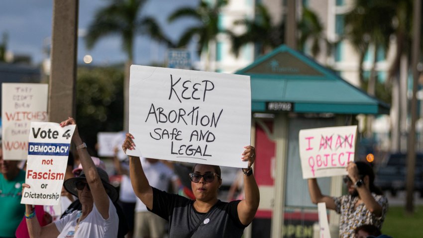 People hold up signs during a pro-abortion rights rally on the second anniversary of the Supreme Court ruling to overturn Roe v. Wade, in West Palm Beach, Florida, on June 24, 2024. (Photo by Marco BELLO / AFP) (Photo by MARCO BELLO/AFP via Getty Images)