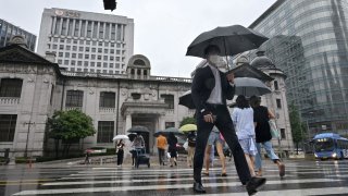 Pedestrians crossing a road in front of the Bank of Korea headquarters in Seoul on July 13, 2022. South Korean economic growth unexpectedly picked up in the second quarter as strong consumption on eased Covid-19 restrictions offset poor exports, supporting the case for further central bank interest rate hikes.