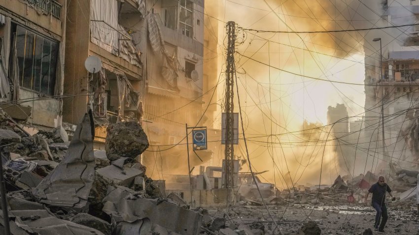 A man runs for cover as a smoke raises in the background following an Israeli airstrike.