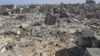 Palestinians walk through the destruction left by the Israeli air and ground offensive on the Gaza Strip near Shifa Hospital in Gaza City