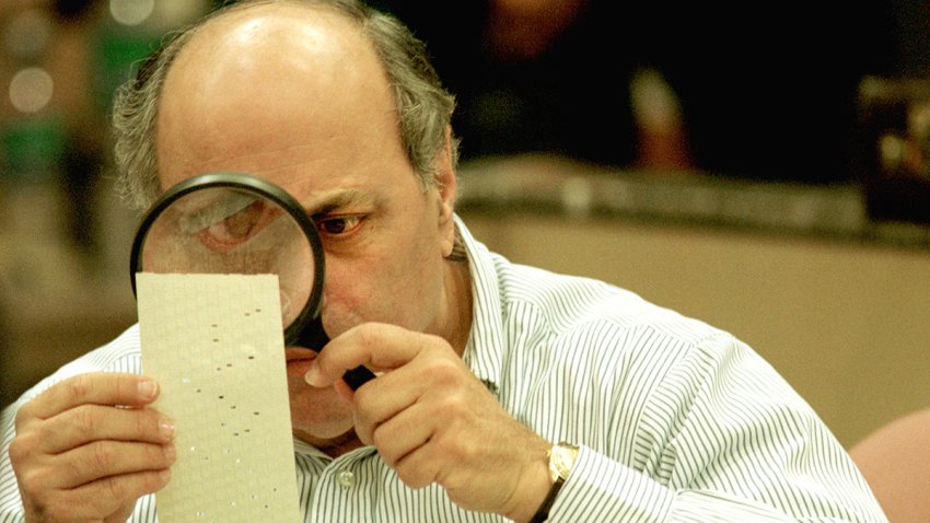 Judge Robert Rosenberg of the Broward County Canvassing Board uses a magnifying glass to examine a dimpled chad on a punch card ballot on Nov. 24, 2000 during a vote recount in Fort Lauderdale, Fla.