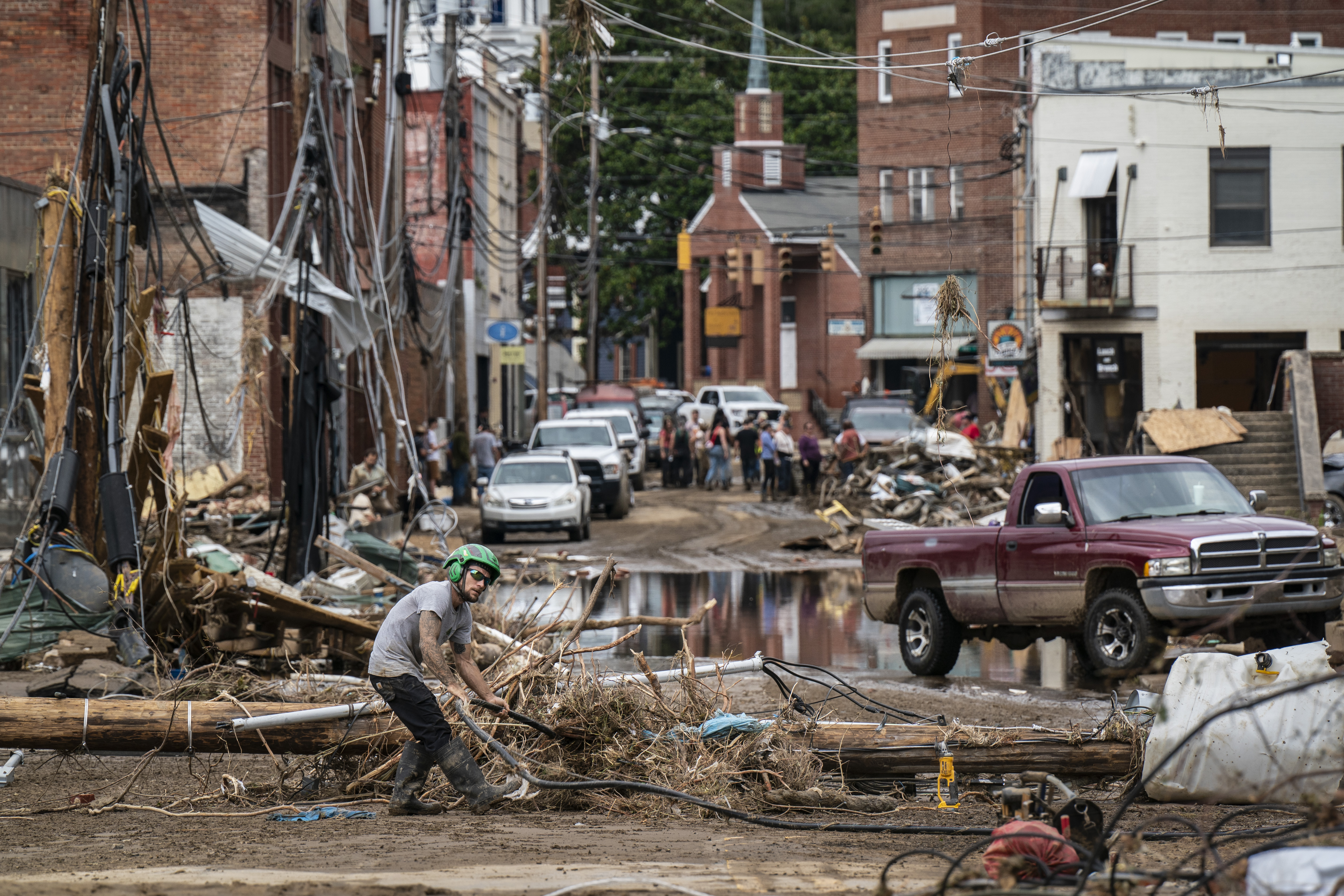 Workers, community members, and business owners clean up debris in the aftermath of Hurricane Helene in Marshall, North Carolina on Monday, Sept. 30, 2024.