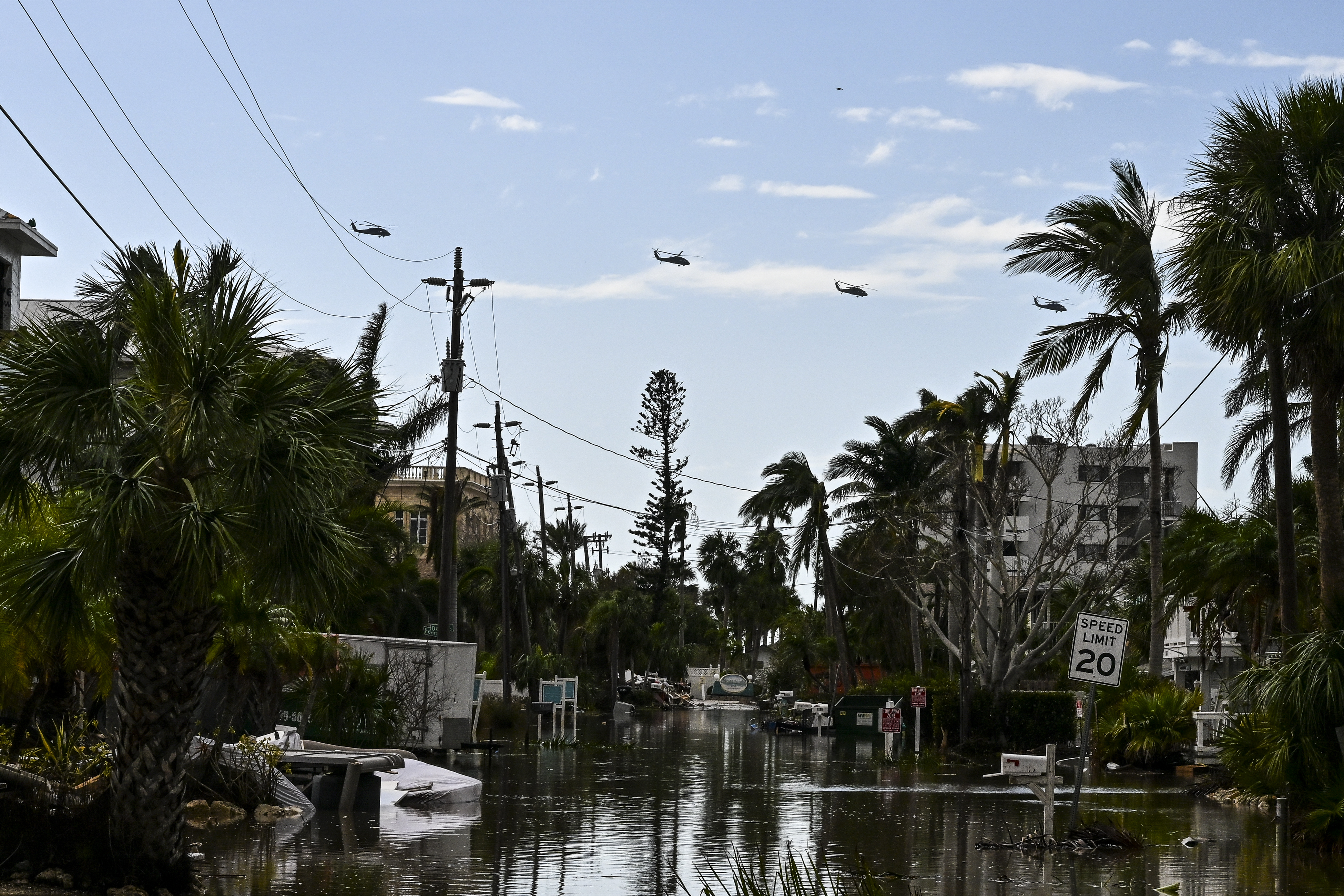 US military helicopters fly above flooded street, in Siesta Key, Fla, on Oct. 10, 2024.