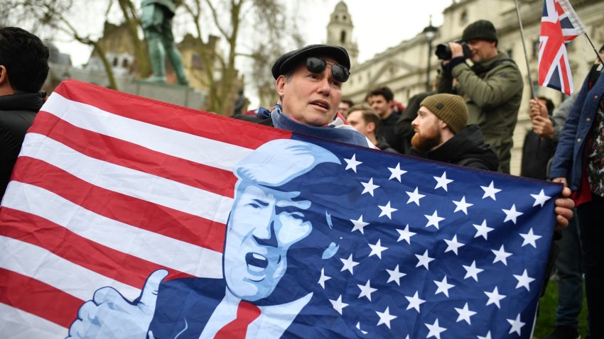 A man holds an American flag depicting president-elect Donald Trump at Parliament Square in London in 2020.