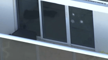 Apparent bullet holes are seen in a glass door on the balcony of a luxury high-rise condo where a man and woman were found shot to death.