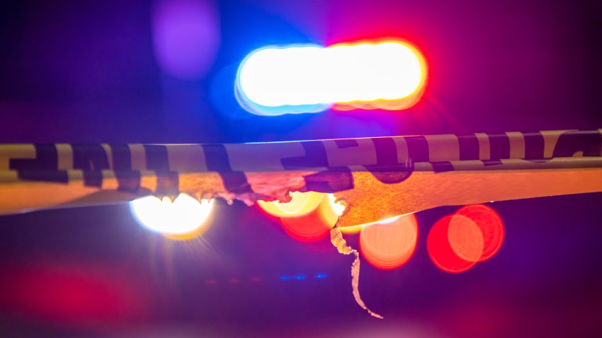 police car sits behind crime scene tape