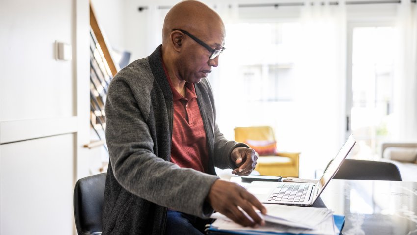 Senior man using laptop and paying bills at home