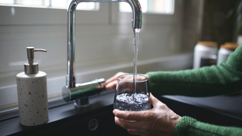 Filling a glass of filtered water right from the tap in the kitchen sink at home.