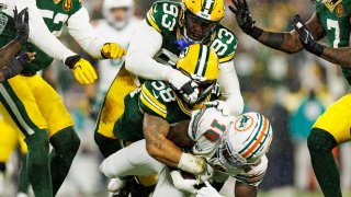 GREEN BAY, WISCONSIN – NOVEMBER 28: Wide receiver Tyreek Hill #10 of the Miami Dolphins is tackled by linebacker Isaiah McDuffie #58 of the Green Bay Packers and defensive tackle T.J. Slaton #93 during an NFL football game, at Lambeau Field on November 28, 2024 in Green Bay, Wisconsin. (Photo by Brooke Sutton/Getty Images)