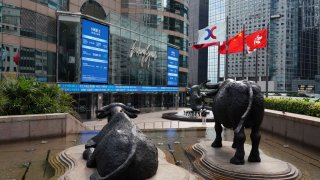 Chinese and Hong Kong flags flutter as screens display the Hang Seng Index outside the Exchange Square complex, which houses the Hong Kong Stock Exchange (HKEX), on January 21, 2021 in Hong Kong, China.