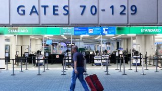 A lone traveler makes his way past a nearly deserted TSA security screening area at Orlando International Airport ahead of the arrival of Hurricane Milton, on October 9, 2024 in Orlando, Florida. 