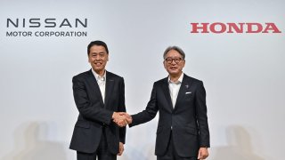 Makoto Uchida (L), president and CEO of Japanese auto maker Nissan, shakes hands with Toshihiro Mibe (R), director, president and representative executive officer of auto maker Honda, following a press conference in Tokyo on August 1, 2024.