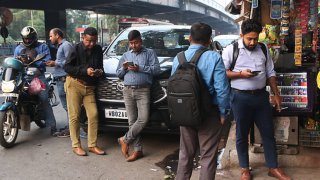 An onlooker checks his mobile phone while watching share prices in Kolkata, India, on November 21, 2024.