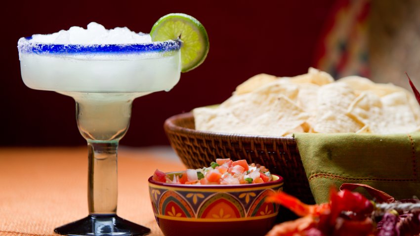 Traditional Mexican Chips, Salsa and Frozen Margarita with salt and lime on the rim of the glass on a table with Mexican decor.