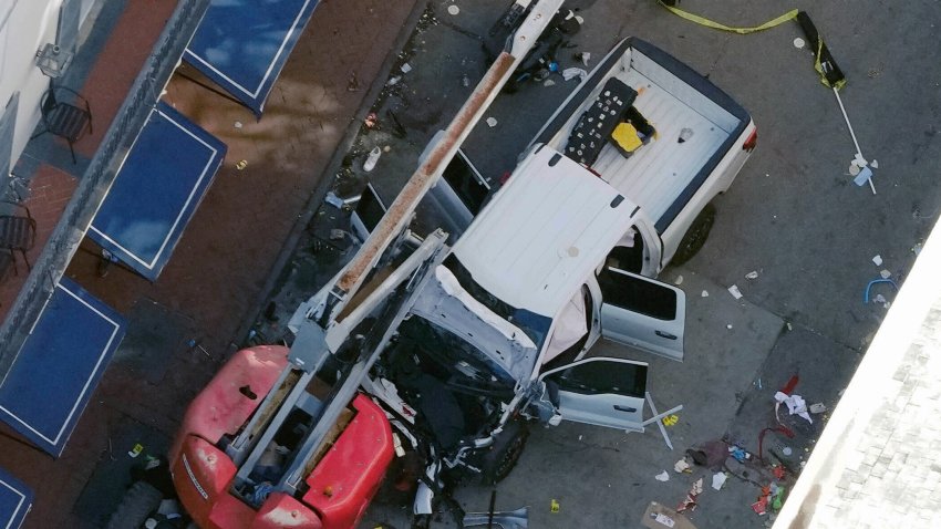 A black flag with white lettering lies on the ground rolled up behind a pickup truck that a man drove into a crowd on Bourbon Street in New Orleans, killing and injuring a number of people, early Wednesday morning, Jan. 1, 2025. The FBI said they recovered an Islamic State group flag, which is black with white lettering, from the vehicle.