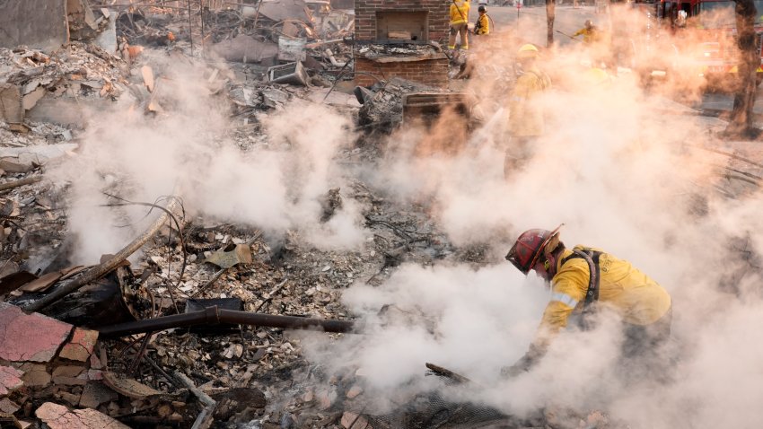 A firefighter clears away smoking debris
