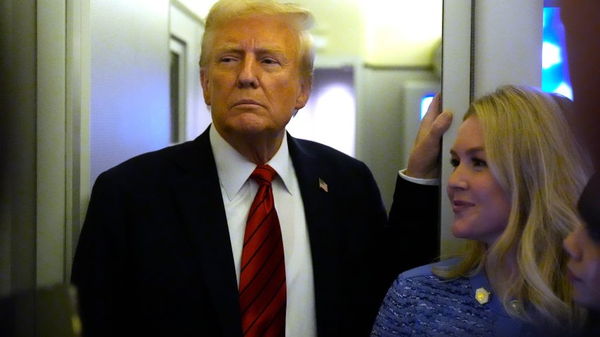 President Donald Trump speaks to reporters aboard Air Force One en route from Miami to Joint Base Andrews, Md., Monday, Jan. 27, 2025, as White House press secretary Karoline Leavitt listens.