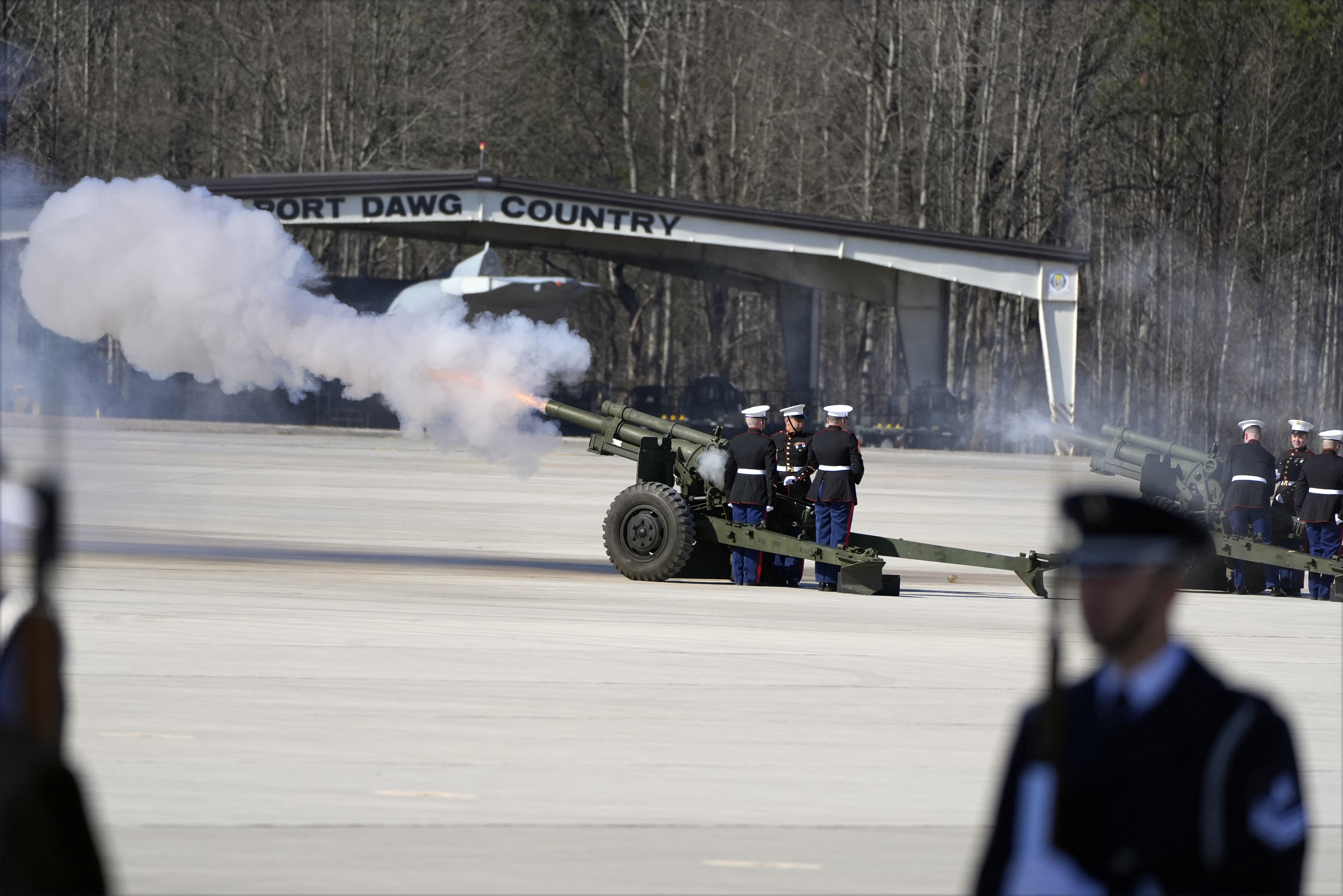 Military members fire a 21-gun salute before the casket is placed into Special Air Mission 39.