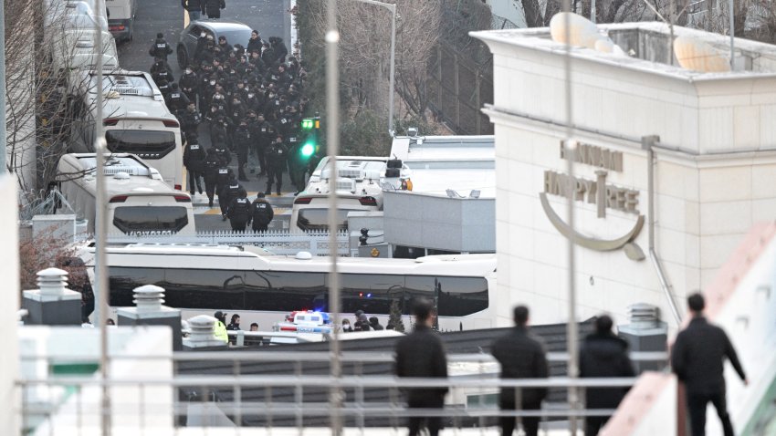 People look at police officers and investigators entering the compound of the presidential residence of impeached South Korea President Yoon Suk Yeol in Seoul, as seen from a hill, on January 15, 2025. South Korean investigators made a fresh attempt to arrest impeached President Yoon Suk Yeol on January 15, 2025 over a failed martial law bid, but were involved in clashes after being blocked by his guards.