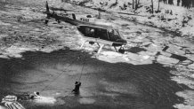 A helicopter drops a line into the frozen Potomac River to rescue survivors of an Air Florida plane crash. 74 of the 79 passengers were killed when the plane crashed shortly after takeoff from Washington National Airport.
