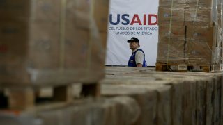 FILE - A man walks past boxes of USAID humanitarian aid