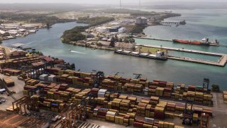 Cargo containers sit stacked as cranes load and unload containers
