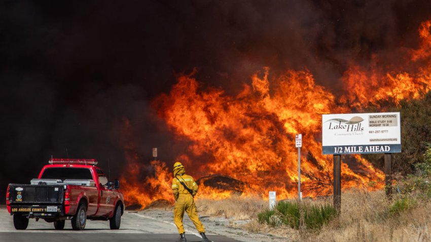 A firefighter and a fire truck backs up from flames and smoke from the Hughes Fire at the Lake Hughes Road in Castaic, a northwestern neighborhood of Los Angeles COunty, California, on January 22, 2025.