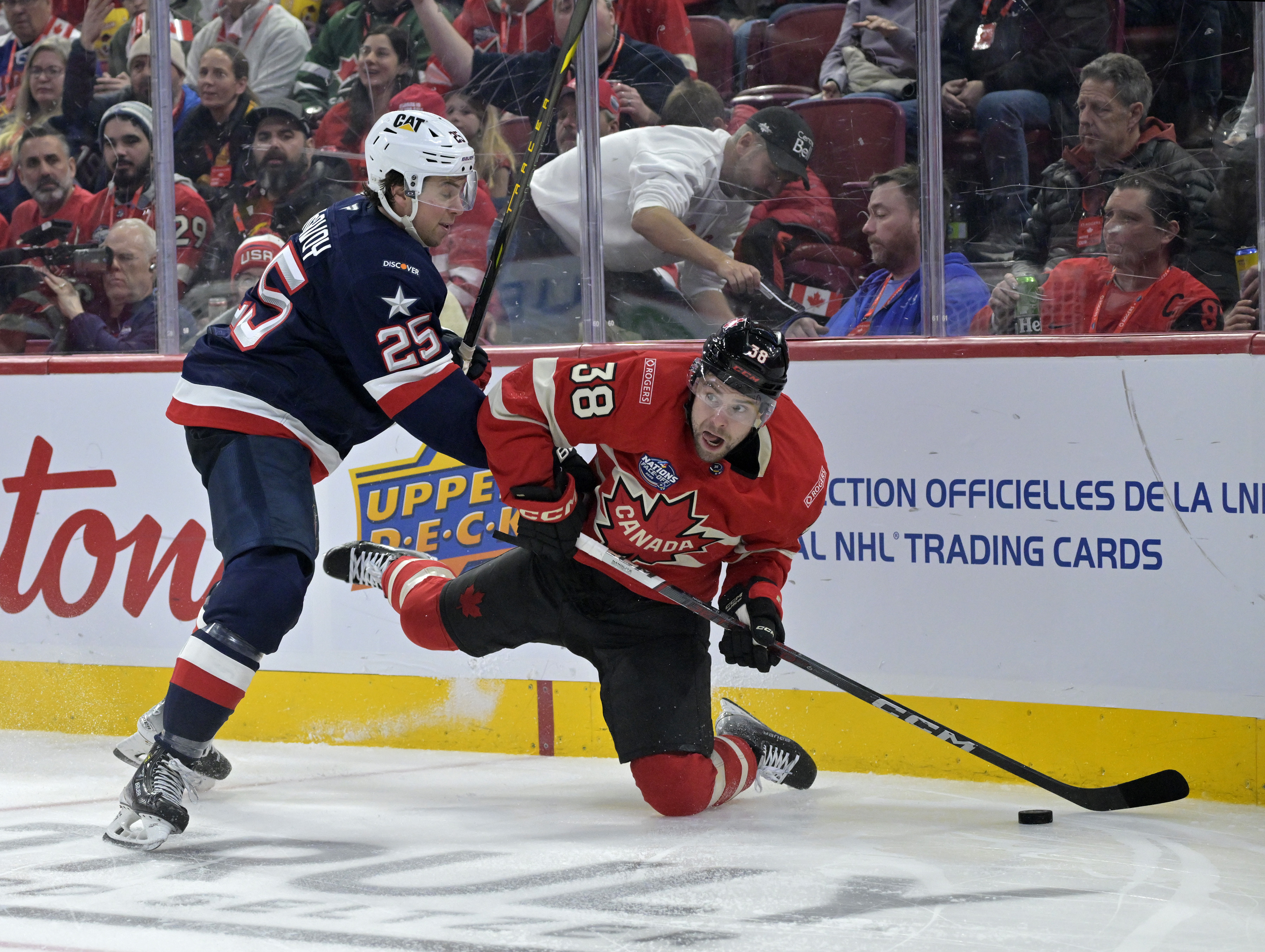 Feb 15, 2025; Montreal, Quebec, CAN; Team Canada forward brandon Hagel (38) plays the puck and Team United States defenseman Charlie McAvoy (25) defends in the second period during a 4 Nations Face-Off ice hockey game at the Bell Centre.