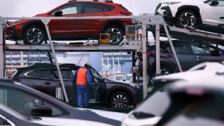 A worker is seen among newly manufactured cars awaiting export at a port in Yokohama, south of Tokyo, Japan, on March 27, 2025.