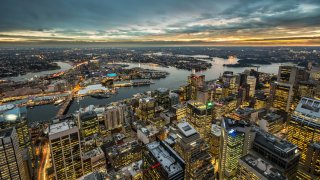 Night shot of Sydney, Australia. Darling harbour in the middle left, looking right out to the horizon where the sun has just set.