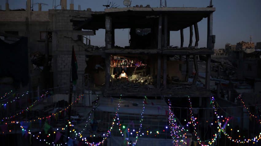 Palestinians hang decorations next to their destroyed homes