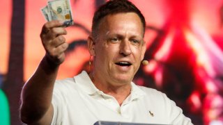Peter Thiel, co-founder of PayPal, Palantir Technologies, and Founders Fund, holds hundred dollar bills as he speaks during the Bitcoin 2022 Conference at Miami Beach Convention Center on April 7, 2022 in Miami, Florida.
