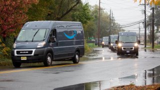 Trucks travel through a flooded road while exiting from an Amazon delivery station in Carlstadt, New Jersey, U.S., on Tuesday, Oct. 13, 2020.