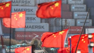 Chinese national flags flutter on boats near shipping containers at the Yangshan Port outside Shanghai, China, February 7, 2025.