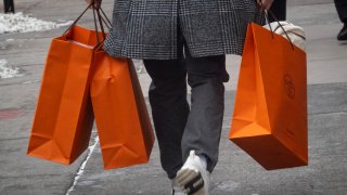 A customer carries merchandise from a Hermes store on Feb. 14, 2025.