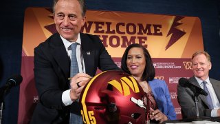 Washington Commanders managing partner Josh Harris (L) signs a Commanders helmet while joined by  Washington DC Mayor Muriel Bowser (C) and NFL Commissioner Roger Goodell (R) during a news conference on construction of a new Commanders stadium on April 28, 2025 in Washington, DC.