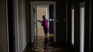 Carole Smith walks through her flooded home